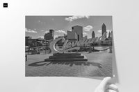 Hang stunning, timeless art in your home with this iconic CLEVELAND SIGN - B&W - 24”x36” gallery print. Boasting a classic black-and-white skyline, this striking landmark will elevate any living space while capturing the essence of Cleveland. Expertly printed on fine art paper, this piece is ready to hang for effortless display in your bedroom, game room, or rec room. Add a touch of charisma and character today! Also available as a ﻿Canvas Wrap.  Note: frame is not included  Designer: @makkersmedia